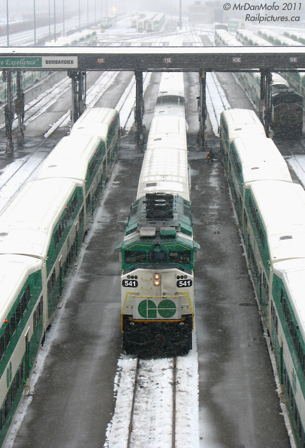 With a winter storm starting to hit hard for the drive home, GO Transit consists are dispatched deadheading from GO\'s Willowbrook Yard to Toronto Union Station, where they will enter service. GO F59PH 541 leads an equipment move with Milton line train #155 into the raging snow. In the distance, the headlight of an eastbound can just be made out.