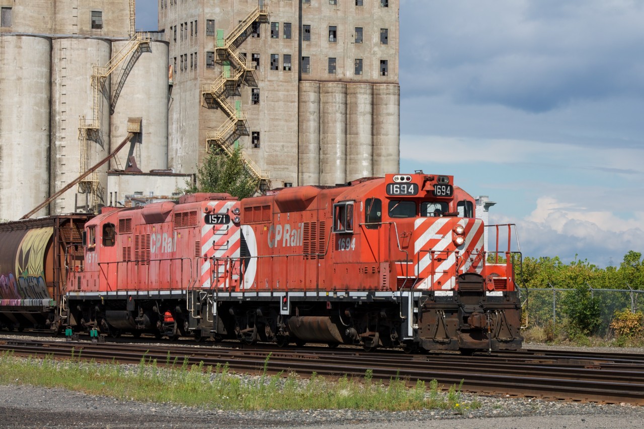 Veteran workhorses CP 1694 & 1571 (both EMD GP9u) haul past the derelict Saskatchewan Pool 8 towards Westfort.