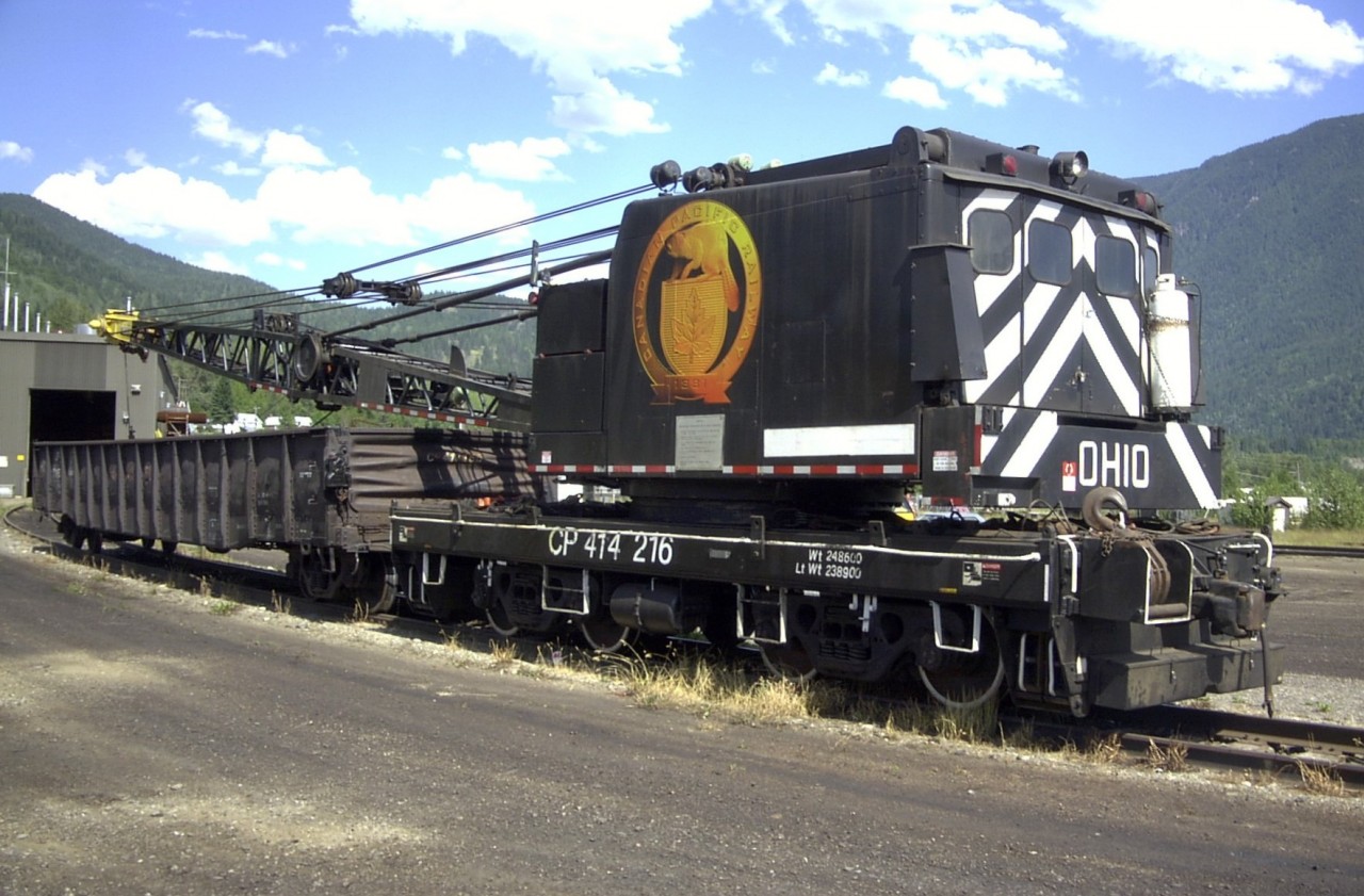 CP 414216, a 1977 built Ohio model DE 400 locomotive crane sits outside the Work Equipment and Car Repair facility in Revelstoke on this sunny and warm July day.  The exterior paint scheme has been slightly modified from CP Work Equipment standards as noted by the large gold Canadian Pacific beaver logo, and the white painted wheel rims, stirrups, and grab irons.  At 35 years of age and still active in 2012, this crane is not considered old by locomotive crane standards.