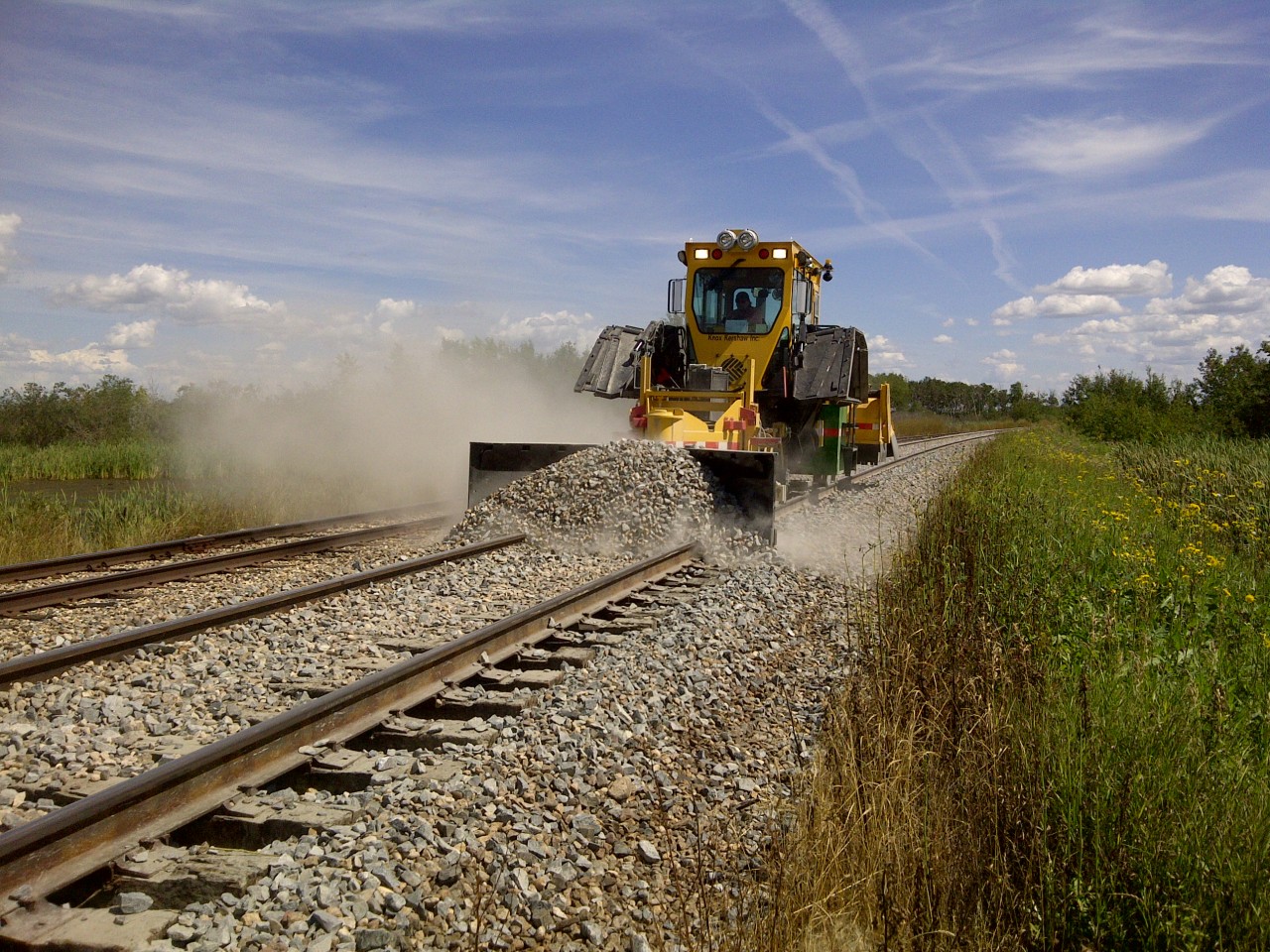 It used to take a lot of men, with a lot of shovels, a lot of hours, to do what this Knox Kershaw KSF940 ballast regulator can do in a matter of minutes. This 2012 version of the KKI machine helps maintain the ballast ahead of and behind the surfacing machine on this CP prairie line.  Proper ballast profiling is essential to maintain adequate drainage and a solid track structure.