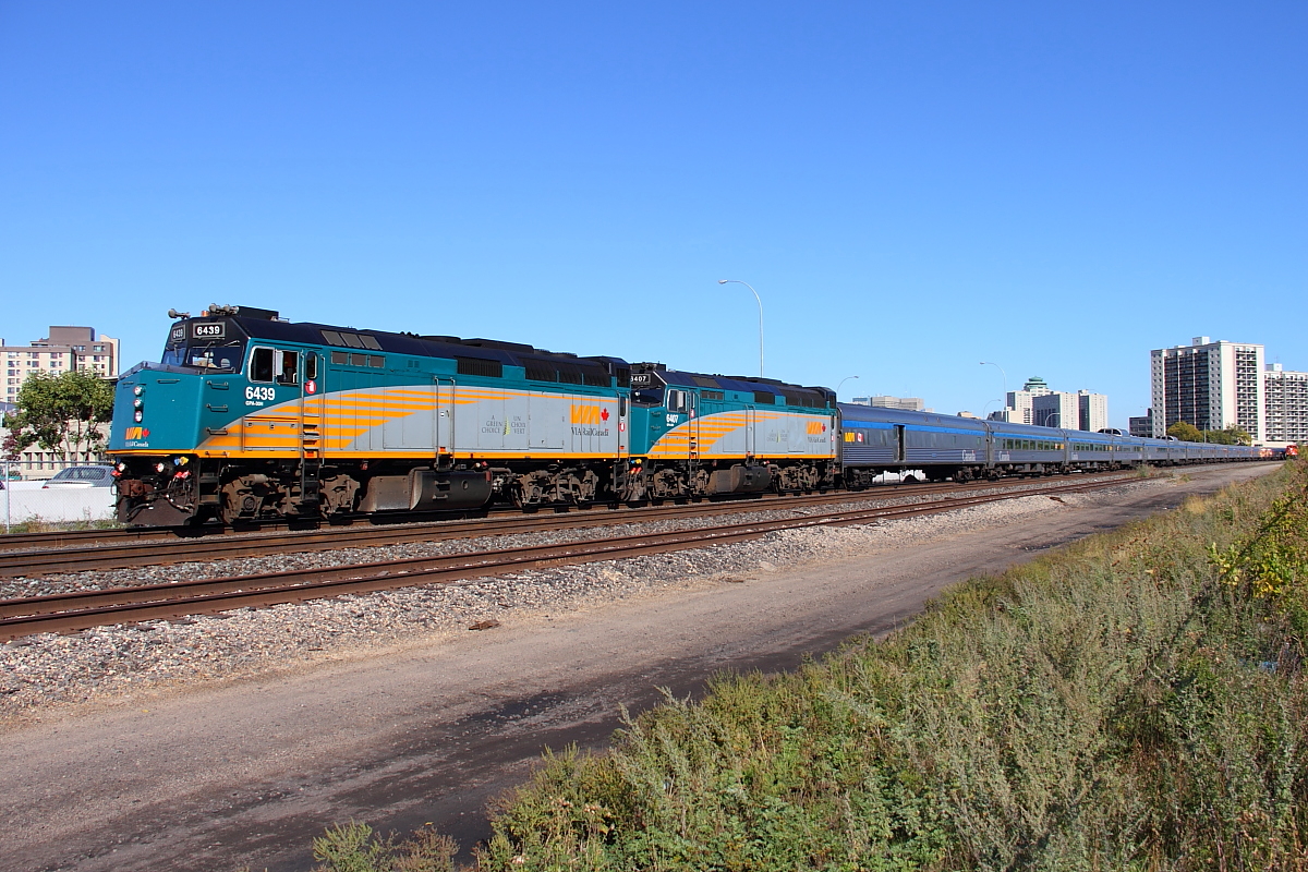 VIA's westbound "Canadian" departs Winnipeg's Union Station, CN intermodal Q199 can be seen on the far right following.