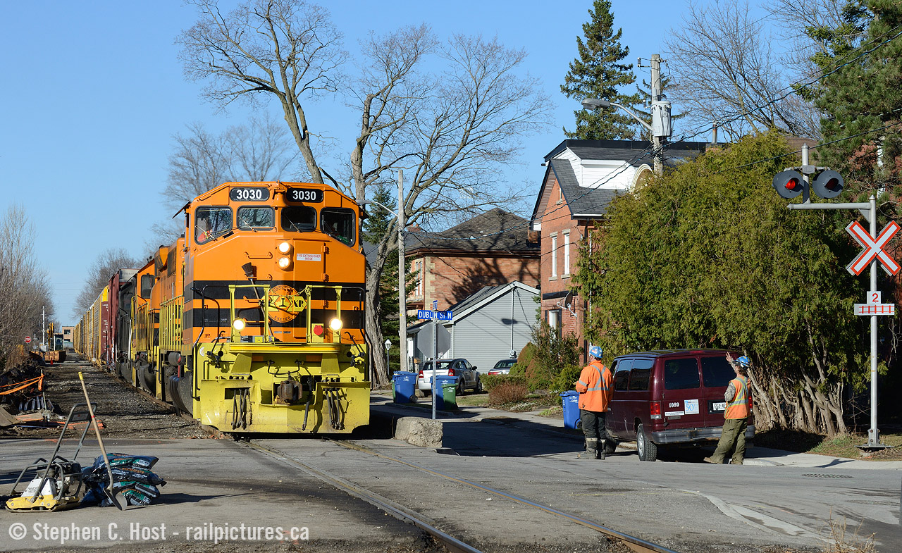 Ch-Ch-Ch-Ch-Changes. PNR track crews wave at GEXR 432 as they pass Kent/Dublin St in Guelph. PNR has been installing new crossing protection along Kent St, a new switch (just behind me) and CTC signals (also just behind me for the MP49 switch and siding).

In this photo, the old protection stands guard warning Kent St. motorists of any nearby opposition on the railway - but this signal will be removed soon. The new crossing protection has been tightened along the right of way removing the need for these old signals for Kent St. It should also be noted that Kent St runs on both sides of the railway - this is in effect fully separated street-running.

All signalled crossings on the Guelph sub are effectively being replaced with CTC compatible equipment.