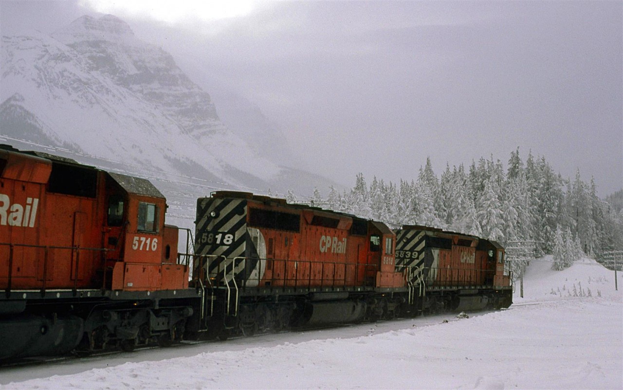 The westbound grain train appears to be diving into the slope that leads down to Field. Cathedral mountain is revealed by a brief split in the clouds.