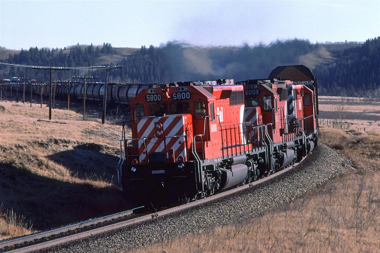 Westbound CP train passing Glenbow siding (Blocked by train). The reason for the icicle clearing car may be seen at the far left - auto racks.