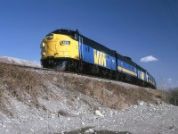 The westbound "Canadian" rounds the curve near the Bearpaw Dam in the Bow River. This is just west of Kieth yard. Some spoils from a large gravel pit may be seen on the horizon in front of the train.