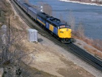 Winter's grip is loosening, at the end of March, but there is still plenty of cold to come. There is still ice on the banks of the Bow River, and buds on the trees are still over a month away. VIA's eastbound "Canadian" approaches the east switch of Brickburn Siding in west Calgary.