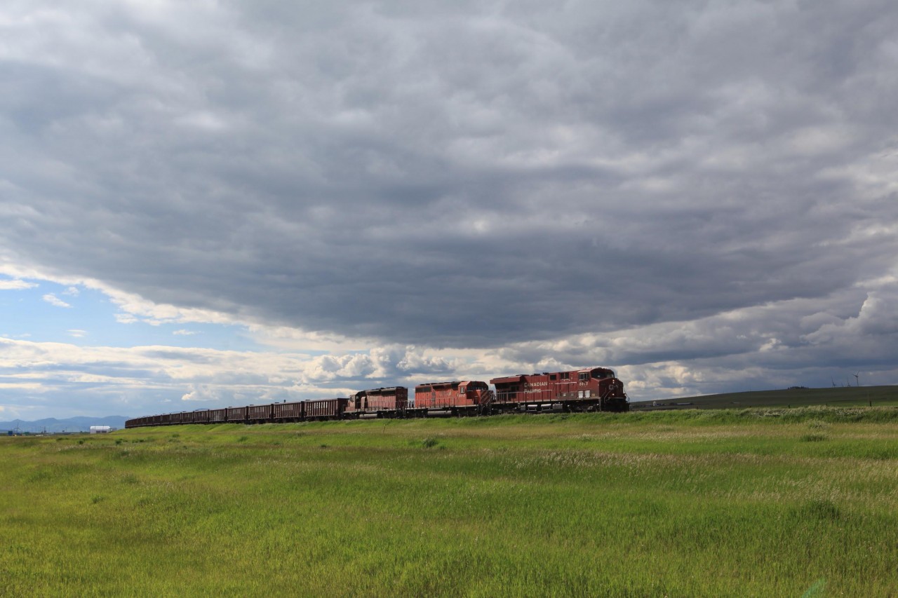 In the evening of June 13, 2015 heavy clouds from the north had eventually moved into the area of Fort MacLeod. 8819, 5717, and 5560 had a ballast train, probably from the quarry west of Cranbrook, BC in tow as they were skirting the edges of these clouds near Pincher Station for a short while.