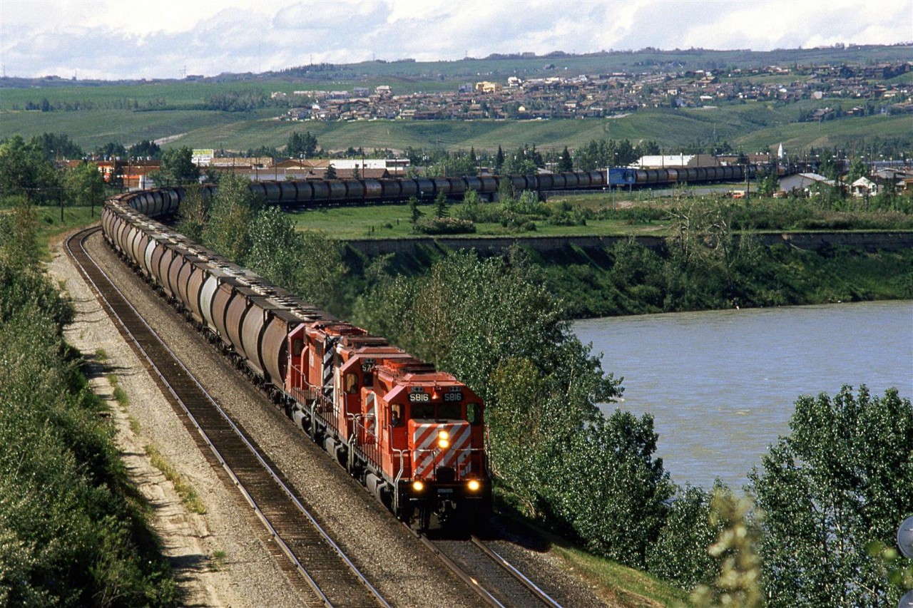 Eastbound potash and grain hopper train at Brickburn. There is a lot more sprawl on those hills in the background these days.