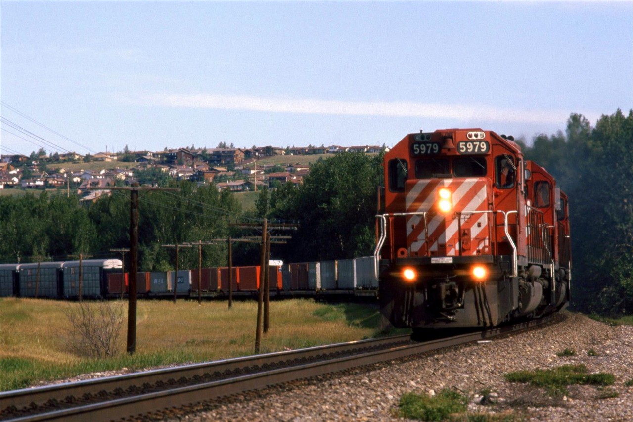 In the mid 80's there was a "Day in the Life of...." craze (for lack of a better word). This was the first railroad-related event - preceding CTC Board's first Day in the West (In a few years it would become all of Nort America) by one day. Someone in St Catherines of Welland was organizing the event and asked photographers to make submissions. I sent is several shots that I had taken that day, but nothing ever became of the project. Nor were my slides ever returned to me. I am still rather ticked. 
This eastbound high priority train is crossing the Bow River out of frame to the left and is about to hit the west switch of Brickburn in west Calgary.