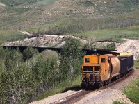 The tail end of a loaded westbound sulphur train snakes along at the foot of Cochrane hill adjacent to the Bow River.
This would be the last photograph that my Mamiya NC1000 would produce. I made the mistake of sitting my camera on my tripod while waiting for the next train. a gust of wind came along (to anyone familiar with the area, I probably did not have to mention this) and knocked the setup over and broke the lens mount. 
There would be a photographic hiatus while I figured out what I was going to do camera-wise.