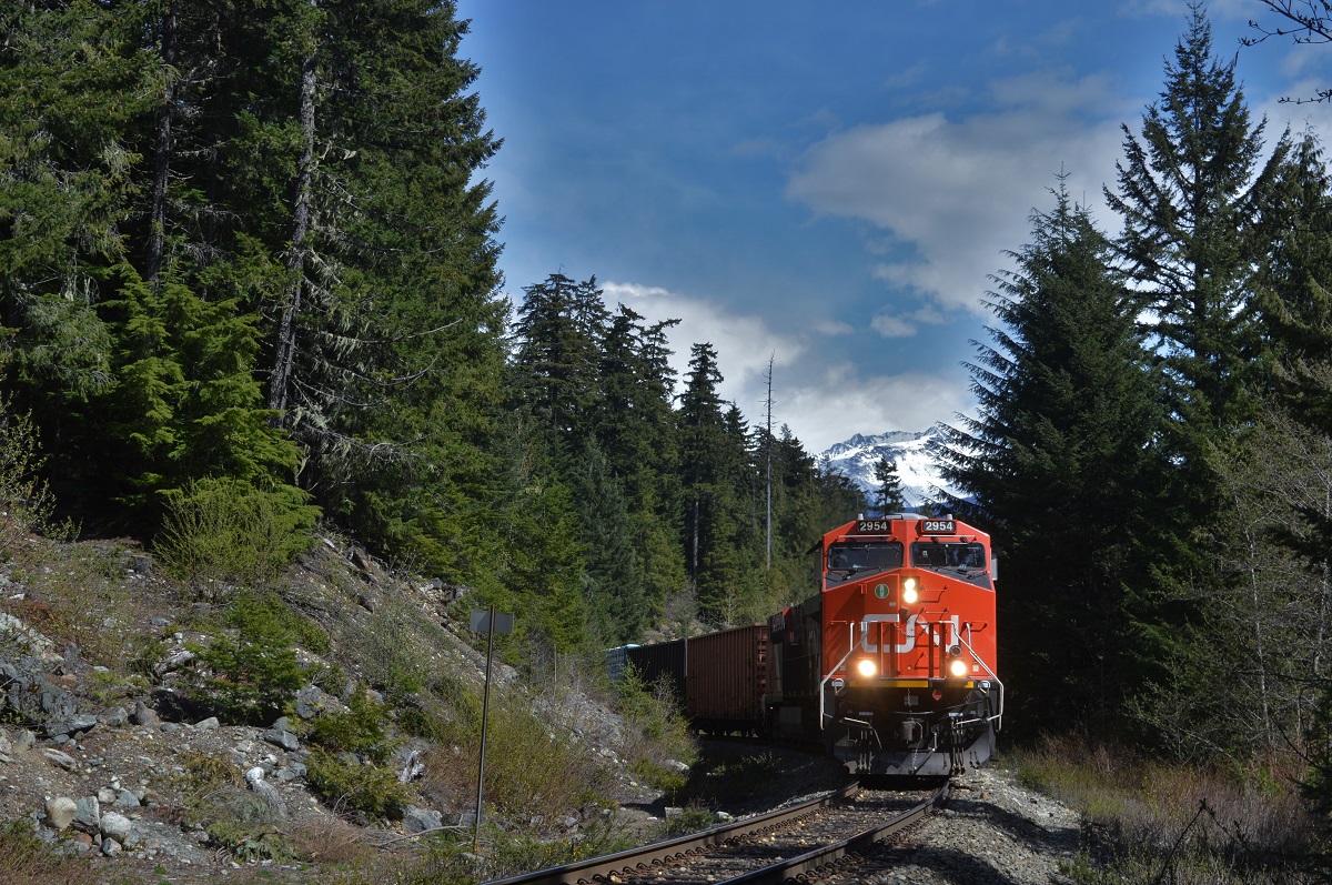 CN 2954 leads CN L570 with 59 loaded cars at Alpha Lake after a meet with northbound counterpart 571 at Mons. Behind the power is a mixed manifest of lumber, woodchips and a sole empty tank that will be refilled with sodium hydroxide in North Vancouver.