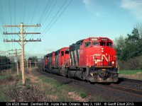 CN 9520 leads a westbound through the curve and is about to pass under the wooden bridge of Denfield Road in Hyde Park, Ontario back on May 3, 1991.