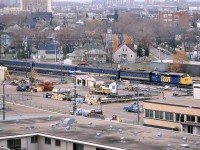 No one is going to call this a great photo, but it is from a relatively unique location - from my apartment on Jasper Avenue (whose rent is probably astronomical compared to back in the depression of '86).
I had watched this train several times, but finally took the time from my studies and pulled my camera out.
The train has finished the stop at the station and is headed NE back to the mainline at East Junction. This loop track to the downtown dates back to when the CN was a series of RR's that came to Edmonton.