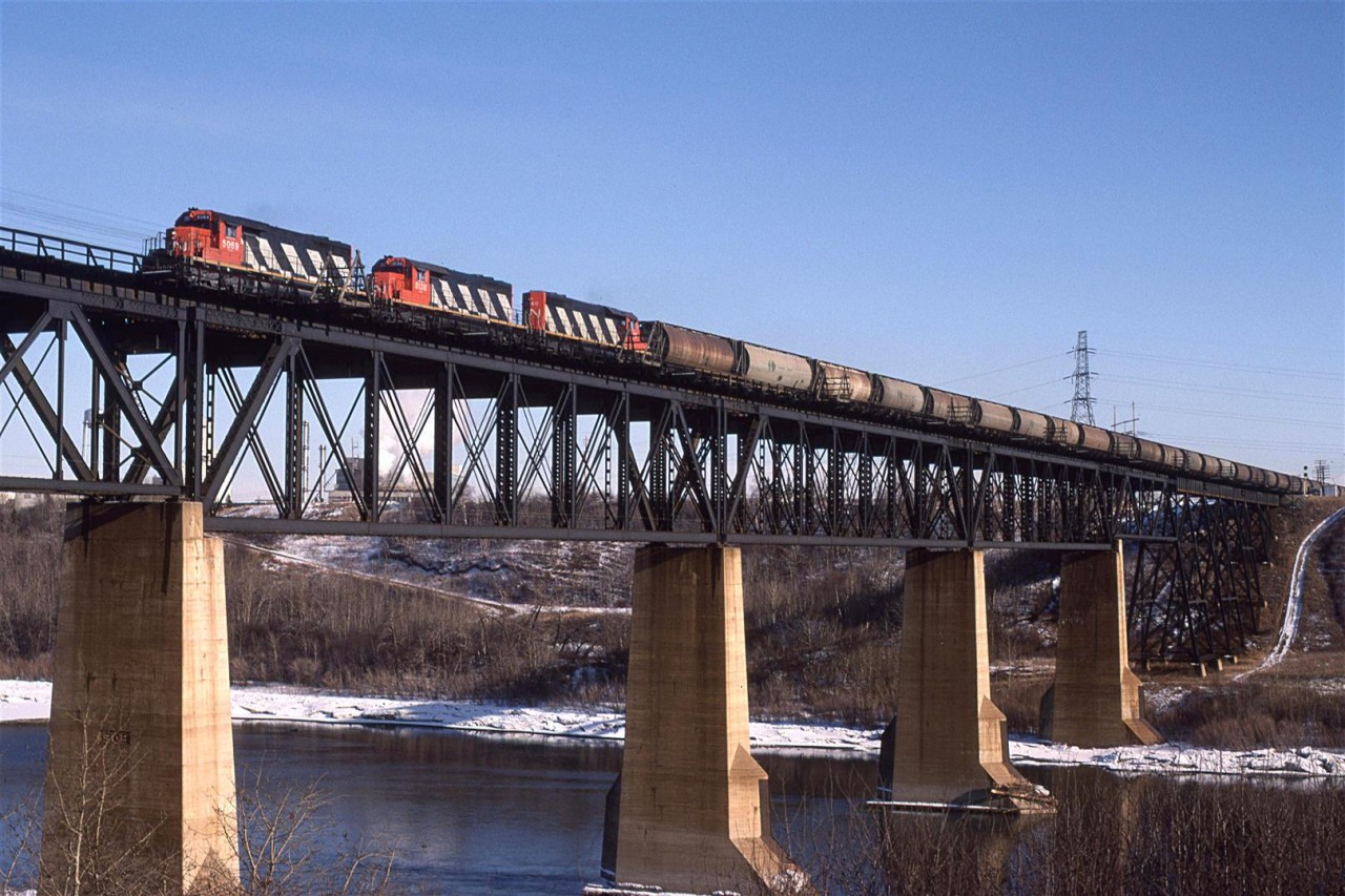 The classic view in Edmonton of CN's Wainwright Sub crossing the North Saskatchewan River on the NE side of the city.
A westbound potash train destined to North Vancouver for export is the subject of this particular show.
Bretville Junction - the connection between the Wainwright Sub (CN's mainline) and the Camrose Sub, that ultimately leads to Calgary, is just across the river at right.
Through the bridge trusses can be seen steam rising from a Celanese chemical plant. It has since been decommissioned.