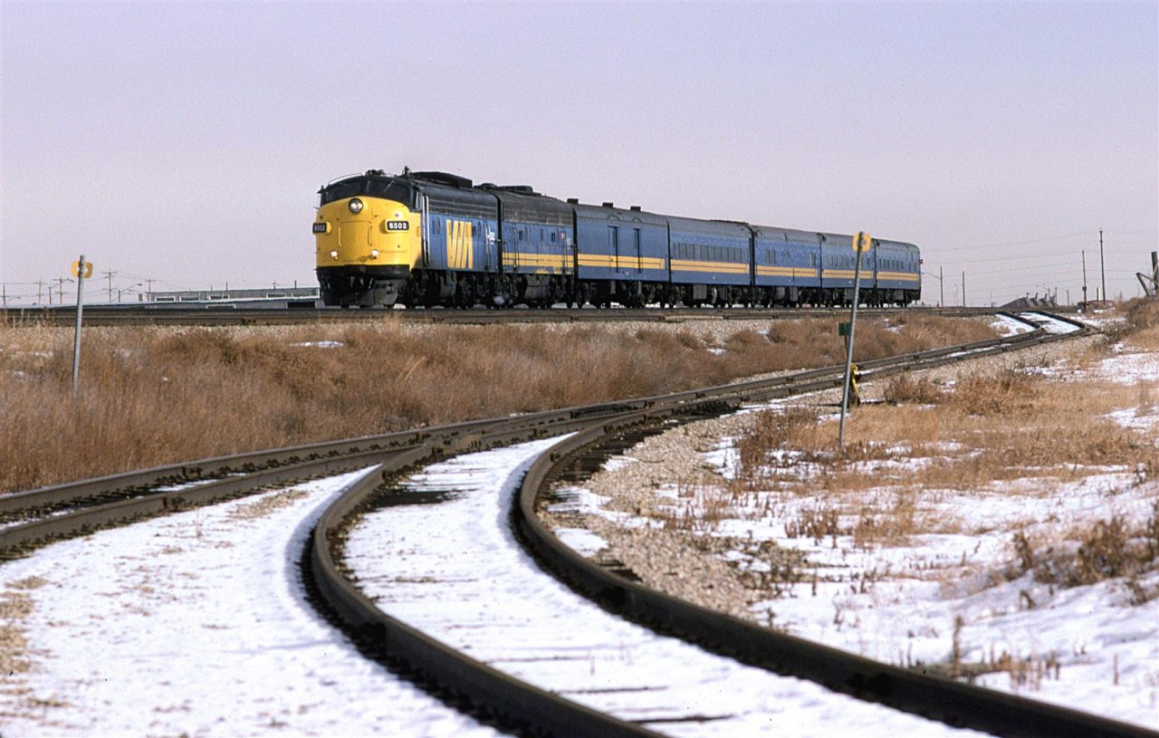 At 1325hrs, the westbound "Super Continental" is about to hit East Junction and head SW to the VIA station. These "drop down" sidings lead to the Swift Premium meat processing plant. The area here, on both sides of the tracks hosted stockyards - many of the paddocks were still in place at this time. There was even a "tunnel" passage under the tracks to connect the areas. These were not active in '87, though.