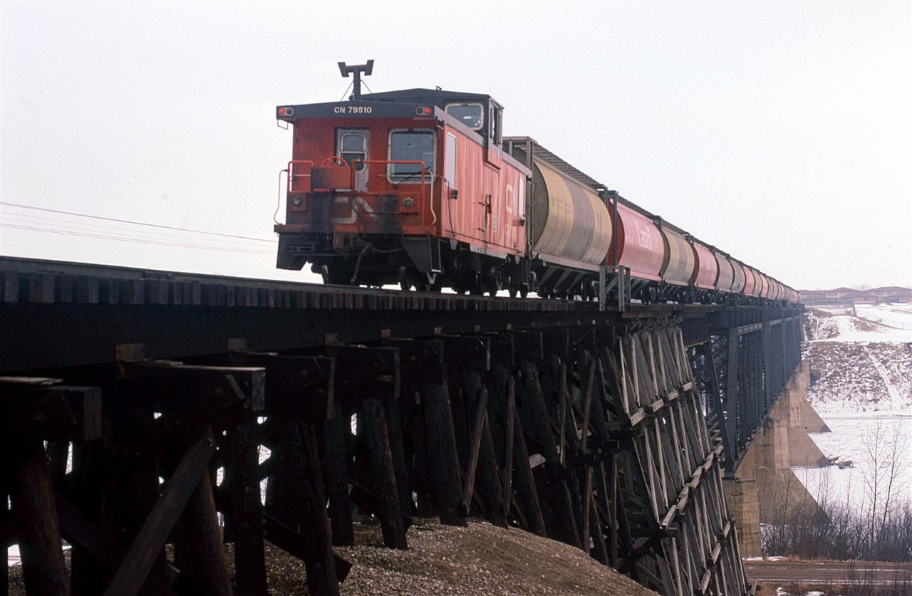 The rear end of an empty grain train crosses the North Saskatchewan River on the Vegreville Sub at Fort Saskatchewan. This bridge would soon be replaced by another further down stream (Geographically NE) of here. The new bridge would allow trains to bypass the town of Fort Saskatchewan. Apart from that, I do not know how they justified the cost of a new bridge. This one looked to be in good shape.
The Vegreville Sub is part of CN's Secondary main between Edmonton and Winnipeg. Fort Saskatchewan is home to several chemical plants - one being Dow Chemical, where my wife worked. She had to zip into work for a short time so she dropped me off by the bridge Without a scanner, I had no idea whether I would see a train. I guess I was hoping for a westbound.