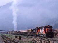 On a very calm summer morning in Boston Bar, the sky fills with smoke from the lumber yard. A couple CN manifest trains await a crew for their eastward journey.
I think that everything associated with the mill is gone.