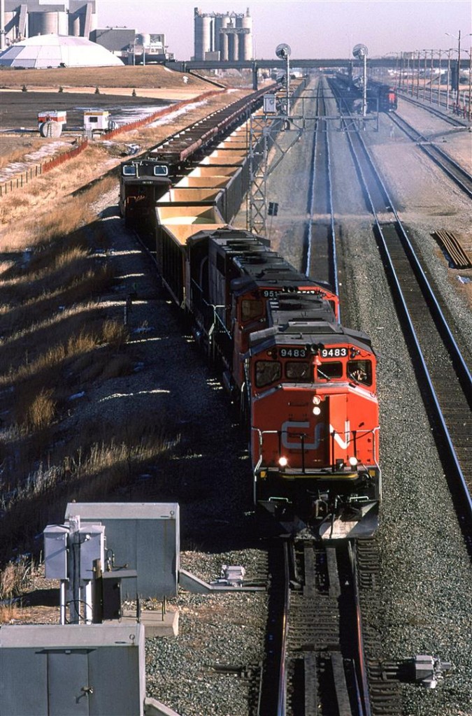 A sulphur train heads west out of Bissell Yard with 3 GP-40's leading. This train originated in the Kaybob area, and will deliver the sulphur to North Vancouver for export.