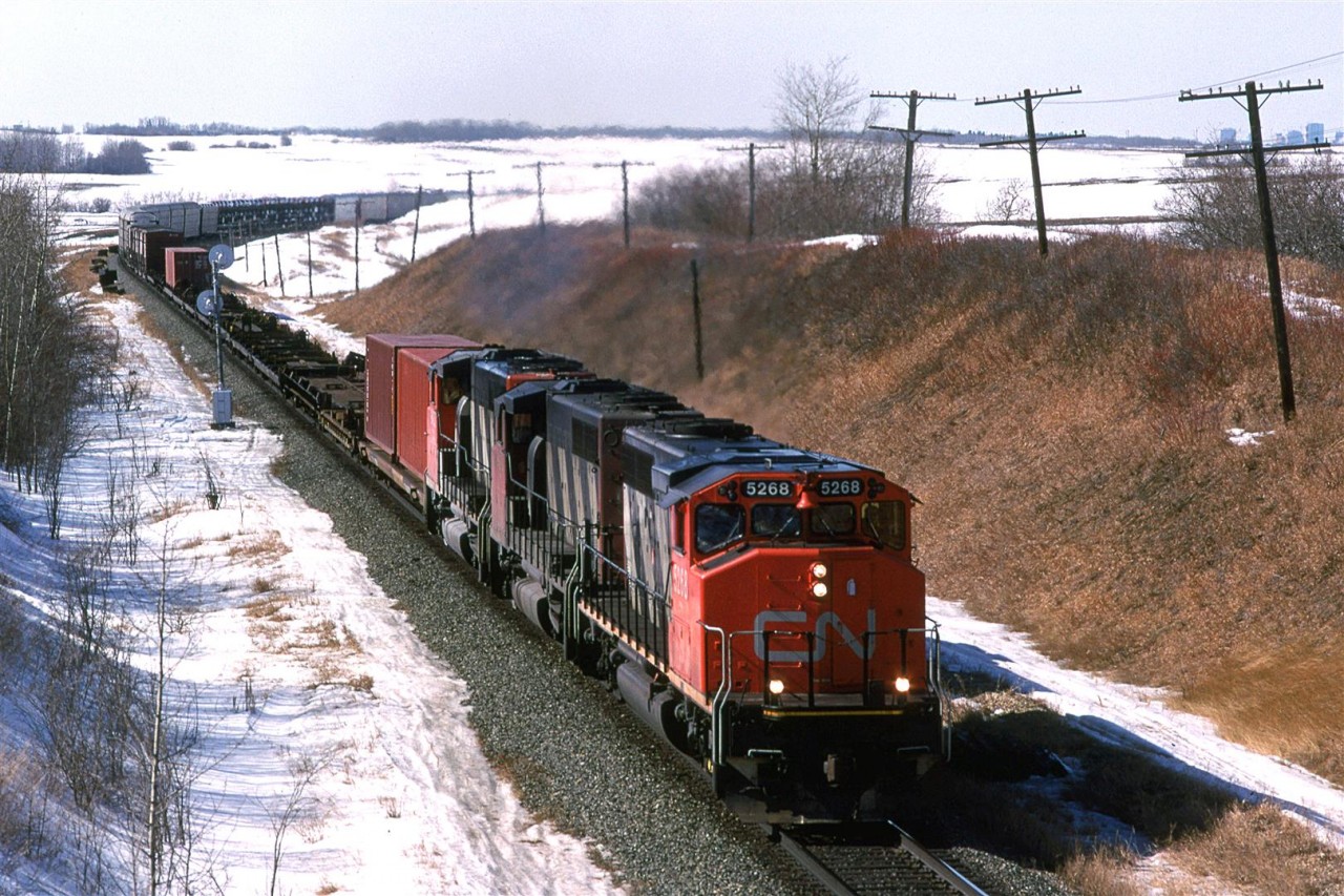 Range Road 224, east of Edmonton, was one of the very few places where there was an overpass for a non-highway. That made it much more pleasant for hanging around (Also, back then, nobody called you in for suspicious activity).
This eastbound auto train is a mystery to me. It might be #164, but it is more likely #204 - a train that I heard on the radio a few times.
Downtown Edmonton can be seen at right and the horizon now has urban sprawl across it.