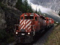 The sun is up, but it is not nearly high enough to reach the heart of "The Big Hill". 
This westbound manifest has just exited the Upper Spiral Tunnel and is approaching the east switch of Yoho Siding. The "Partridge" sign indicates the name of the next siding, uphill from here. 