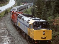 The westbound "Canadian" is about to enter the tiny tunnel just past the west switch of Cathedral Siding. Once again, there is a CP unit in the consist this day. Odd.
It may look like CP made a bargain with VIA - in exchange for the SD40, CP could tack on some grain hoppers. Well, that is not the case. There is an eastbound train in Cathedral Siding (The caboose may be seen above the prominent dome car.