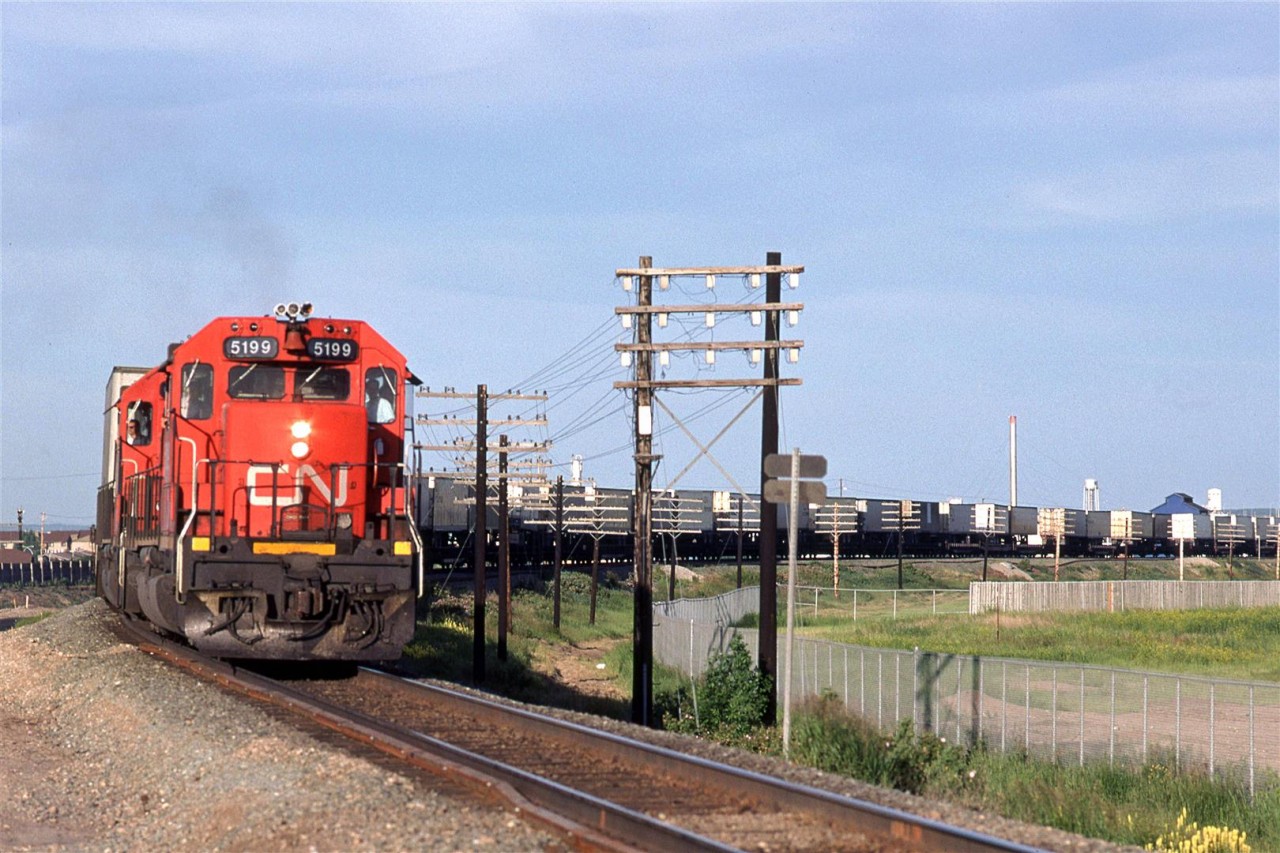 I am a morning person and as such, I would do most of my railfanning then. But that was becoming somewhat predictable, so I decided to try my hand with the sun in the western sky. The problem with evenimgs in Edmonton is that there are so many summer days that start out clear but cloud up throughout the day, with rain at dinner time and diminishing clouds after that.
I caught #201 arriving at 50th in Edmonton - TOFT and pole lines. Domtar's blue building is still standing, also.
I would soon learn that most of CN hot trains would hit Edmonton in the early evening hours.