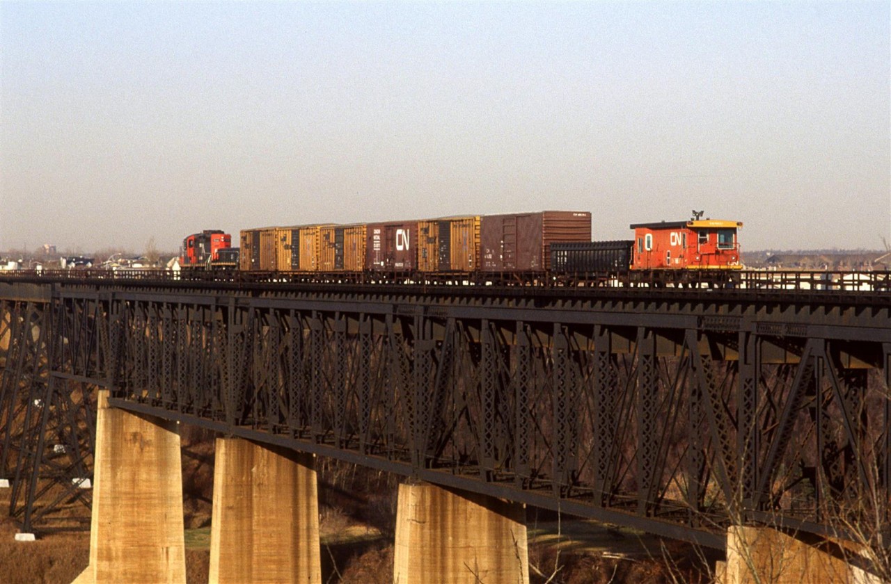 A "Clover Bar Transfer" (one of many during the day) is returning to Calder/Walker Yard. It is crossing the high bridge over the North Saskatchewan River in NE Edmonton. The style of caboose used on the transfer and switch movements was typical.