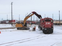 The jaw attachment on the excavator gets started on picking apart SD40-2 CP 6623 by removing the winterization hatch on the cooling fans.