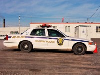 Railway Police Ford Crown Victoria wearing the golden beaver logo on a royal blue backing parked at Oshawa Yard. A smokestack from GM's automotive plant can be seen in the background.  