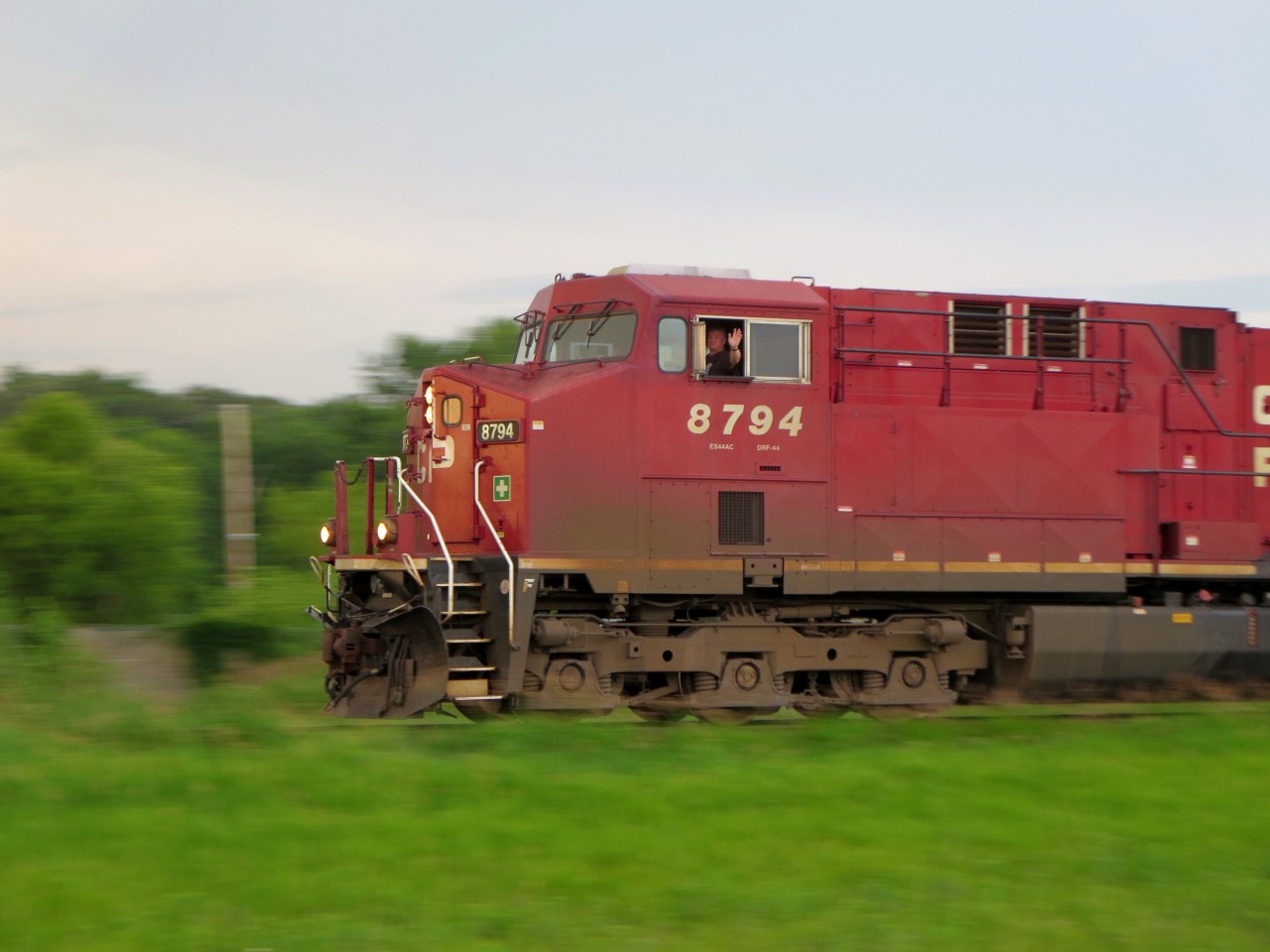 With a friendly wave from the cab, CP 8794 West rolls past the Starbuck west mileboard with a train of 109 grain empties headed for the Viterra grain elevator at Fannystelle, MB