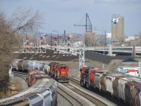 GE's built 28 years apart meet as CN 527 with CN 2110 leading is passed by grain train CN 874 with CN 3191 and 3227 up front (and CN 3887 is on the rear). CN 527 has CN 3058 and CN 8816 trailing and is stopped before it backs up to drop off cars on Track 29. CN 874 has 121 grain loads and is about to change crews at Turcot Ouest before continuing on towards Quebec City.  At far left, grain cars are stored on the transfer track and CN 527 has some grain cars in its consist as well.