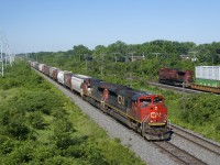 CN 322's head end and CP 112's rear DPU are pacing each other as they approach a pedestrian overpass in Beaconsfield. CN 322 has 160 cars and weighs in at nearly 20,000 tons, with most of the train consisting of grain cars for Montreal. Power is CN 8101 and IC 2465 up front and CN 2288 and CN 2441 mid-train, CN 2441 being one of the few CN cowls currently in service.