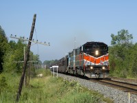 A rail train is passing the Rosedale station sign at MP 119 of CP's Winchester Sub, which is being converted from double track ABS to single track CTC. Power is CMQ 9017 and CMQ 9011 and the train is en route to pick up rail from the now ripped-up north track.