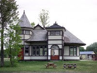 The Grand Trunk extended the original Georgian Bay & Lake Erie Railroad to Wiarton from Owen Sound in 1882. Lot of fanfare that opening day Aug 1st, with a 13 car train and a extensive celebrations. The GTR built a new and improved station in 1904, which is the one pictured. At one point there was also a turntable and roundhouse in town. Roundhouse came down in the 1930s and the turntable was removed in 1961. Passenger service southward was achieved by the train coming out of Owen Sound to the Jct for Wiarton, and backed into town for riders. This service ended in 1957. Freight service ended around 1971 and in 1972 no more trains ran. By 1980 the track was gone. Wiarton station was saved and moved to Bluewater Park near the harbour. Old postcards and photos show an extension that is not seen in this photo. That was the freight shed on the end, dismantled in 1972. The photo here shows the back of the station, the customer entrance, as it was more stylish. In 2004 where the freight attachment was, a new addition was added, (left side in photo) similar in size to the old, but rather open-air and is used as a pavilion.  The town fire hall occupies the location where the station originally stood. The rather unusual structure currently serves as a museum and tourist bureau, and the town takes great pride in their landmark.