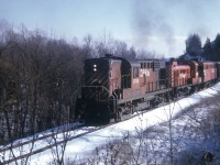 Back in the day when locomotives were nowhere near as powerful as todays, it took quite the effort to climb up the grade from Hamilton toward Guelph Jct. CP 8740 (RS-18) with CP 8446 (RS-3) and an unidentified F unit are seen working hard in this view taken near the Mill St underpass just south of Waterdown proper.