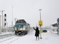 A station attendant greets VIA 67 as it arrives at Dorval Station towards the end of a snowstorm. She is taking a break from building a snowman; seen at bottom right.