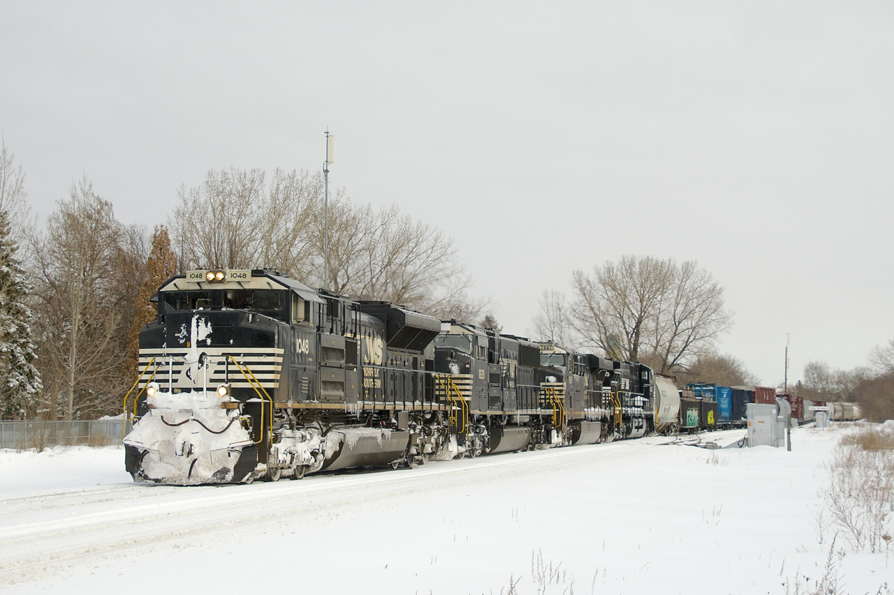 The day after a snowstorm, two days worth of CN 529 have been combined and the train is a few miles from Taschereau Yard with NS 1048, NS 1828, NS 7667, NS 4303 and 54 cars. A crew had taxied down to Rouses Point to pick it up.