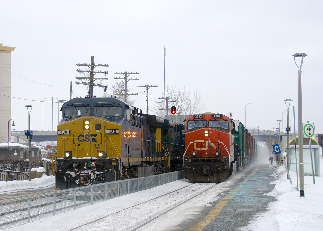 CN 305 is blasting by a CN 327 which is stopped in front of Dorval Station on a cold and windy afternoon. With CN 149 not too far ahead with engine problems and a number of VIA trains in the mix, CN 327 will be cooling its heels here for a little while before being able to continue westwards.