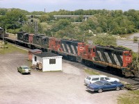 Nice sunny mid-afternoon. Not sure of this train number; but guessing it is the "pulp train" on account a quartet of GP9s for power; and they were based at Fort Erie or Niagara Falls for the most part back then. Lashup makes for a nice scene; CN 4565, 4495, 4527 and 4571 are the numbers.
Autos in scene......my old blue Cougar, next to it (the late) Bill McArthurs chev wagon; and the little green heap I have no info on.