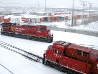 On a snowy morning, CP 112's mid-train DPU (CP 8046) is temporarily tied down at left, as the head end power shoves a last cut of intermodal cars into Lachine IMS Yard.