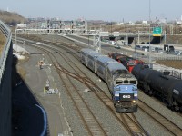 A crewmember watches on as EXO 1207 passes CN 306 at Turcot Ouest, which is stopped and changing crews.