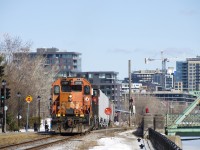 The Pointe St-Charles switcher is crossing Charlevoix street with 6 grain cars for Ardent Mills. At left is a light for a new walking/bike path which parallels the East Side Canal Bank Spur.