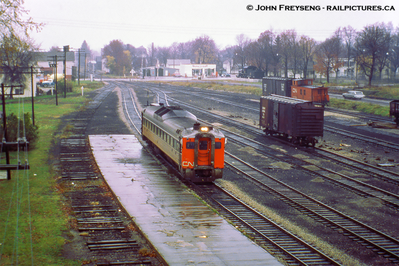 Last CN Passenger service at Palmerston, part 1.  Operating as an extra, formerly running as train number 672 - the southbound RDC-1 passenger car from Owen Sound - coasts into Palmerston on Saturday, October 24, 1970 for the final time. Arriving at 0655h, the Railiner will be moved from the Fergus Sub side of the station over to the Newton Sub side to await the arrival of Extra 6354, formerly train 668 (RDC-2) from Southampton. Both will be combined and having met extra 6118 (RDC-1), the former train 662 from Kincardine, will depart at 0715h for the trip to Toronto (formerly train 658) via the Fergus, Guelph, Halton, and Weston Subs. Extra 6118, which had arrived at 0700h from Kincardine, will too depart at 0715h for Stratford.I believe the official last runs of the RDC service to Owen Sound, Kincardine, Southampton, and Goderich was the evening of Fri Oct 23, 1970. Although the Sat runs to Toronto (and Stratford) carried passengers, they were no longer operating as scheduled trains, hence the extra flags. Daylight Saving time ended early Sunday morning, Oct 25, 1979, and CN and CP would bring out their winter timetables at this time change.Note Canadian National 81 in the distance. The E-10-a mogul, built in 1910 by CLC as GTR 1001, E12 class. Later renumbered CNR 903 in 1923, and finally CNR 81 in 1951. She was donated to the City of Palmerston in 1959 and remains there well taken care of today.John Freyseng Photo, David Warne Collection slide.