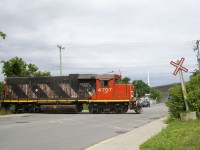 The conductor waves after flagging the busy Monk Boulevard crossing as the Pointe St-Charles Switcher departs the Turcot Holding Spur with two cars, after having dropped off one.