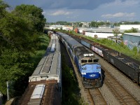 EXO 1211 is westbound just 10 seconds after the head end of CN 321 passed on the right. At left are parked grain cars. CN 321 has the usual large cut of gons, EXO 1211 has AMT 1343 and four multilevel cars.