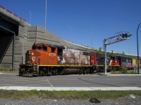 The Pointe St-Charles Switcher is crossing Notre-Dame Street, on its way to bring cars to the Kruger plant. The train is about to go under the rebuilt Turcot interchange.