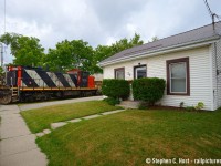 A lady looks out her front door to witness a GMD-1 in her driveway and Engineer Doug Blue rings the bell for Crimea st as they round the wye in Guelph. With a storm quickly approaching, L542 would basically park their train for lunch, for in a few minutes there will be a torrential downpour as a severe storm hit town. 