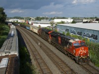 A CN 100 unit leads CN 321 as it passes parked grain cars.