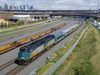 VIA 67 has two F40's up front (VIA 6459 & VIA 6407) as it passes stored well cars, as well the skyline of downtown Montreal.