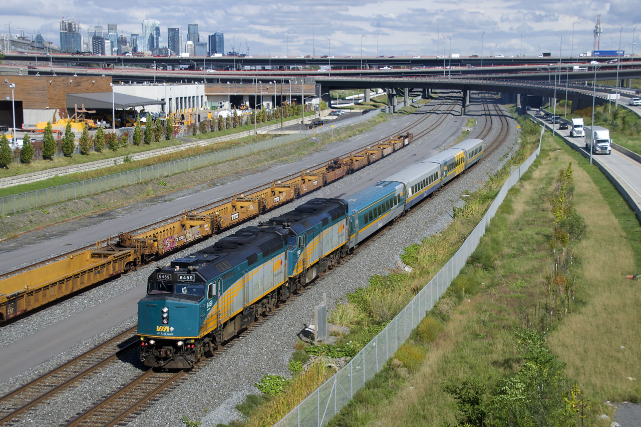 VIA 67 has two F40's up front (VIA 6459 & VIA 6407) as it passes stored well cars, as well the skyline of downtown Montreal.